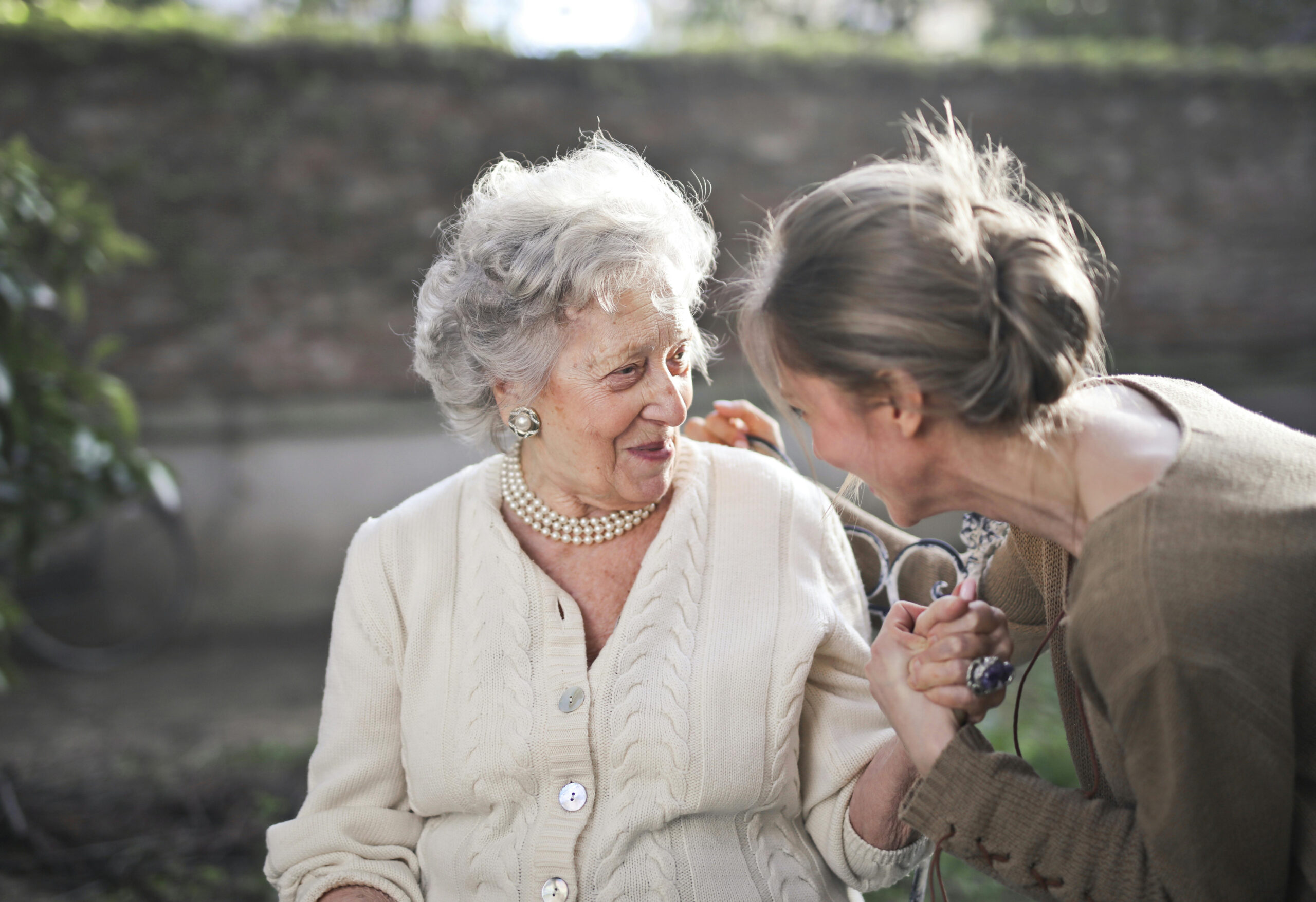 Senior Woman being embraced by adult daughter