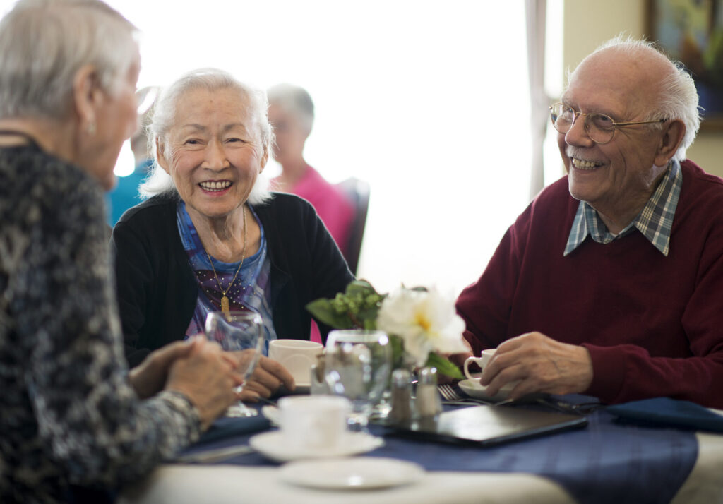 A group of senior adults are having a meal together. They are sitting at a table and are talking among themselves.