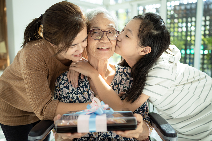 Three generations share a hug in this bright photograph showing a gift-giving moment for grandma.