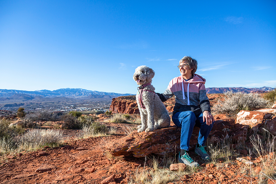 Senior woman hiking with dog in the Arizona desert at sunrise