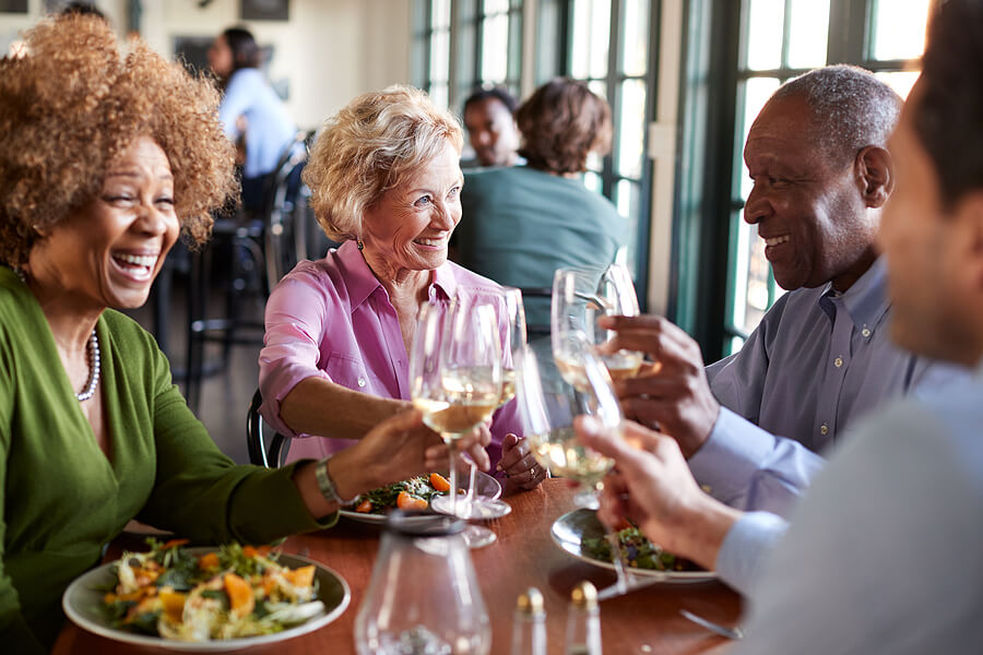 Group Of Smiling Senior Friends Meeting For Meal In Restaurant