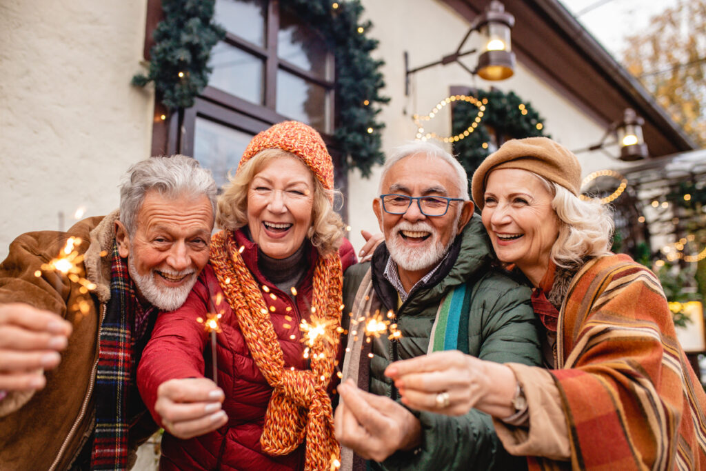 A group of senior friends in winter attire hold sparklers and get festive