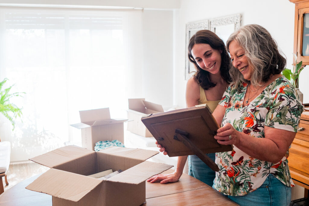 An adult daughter helps her senior mother pack, offering tips on downsizing for seniors.