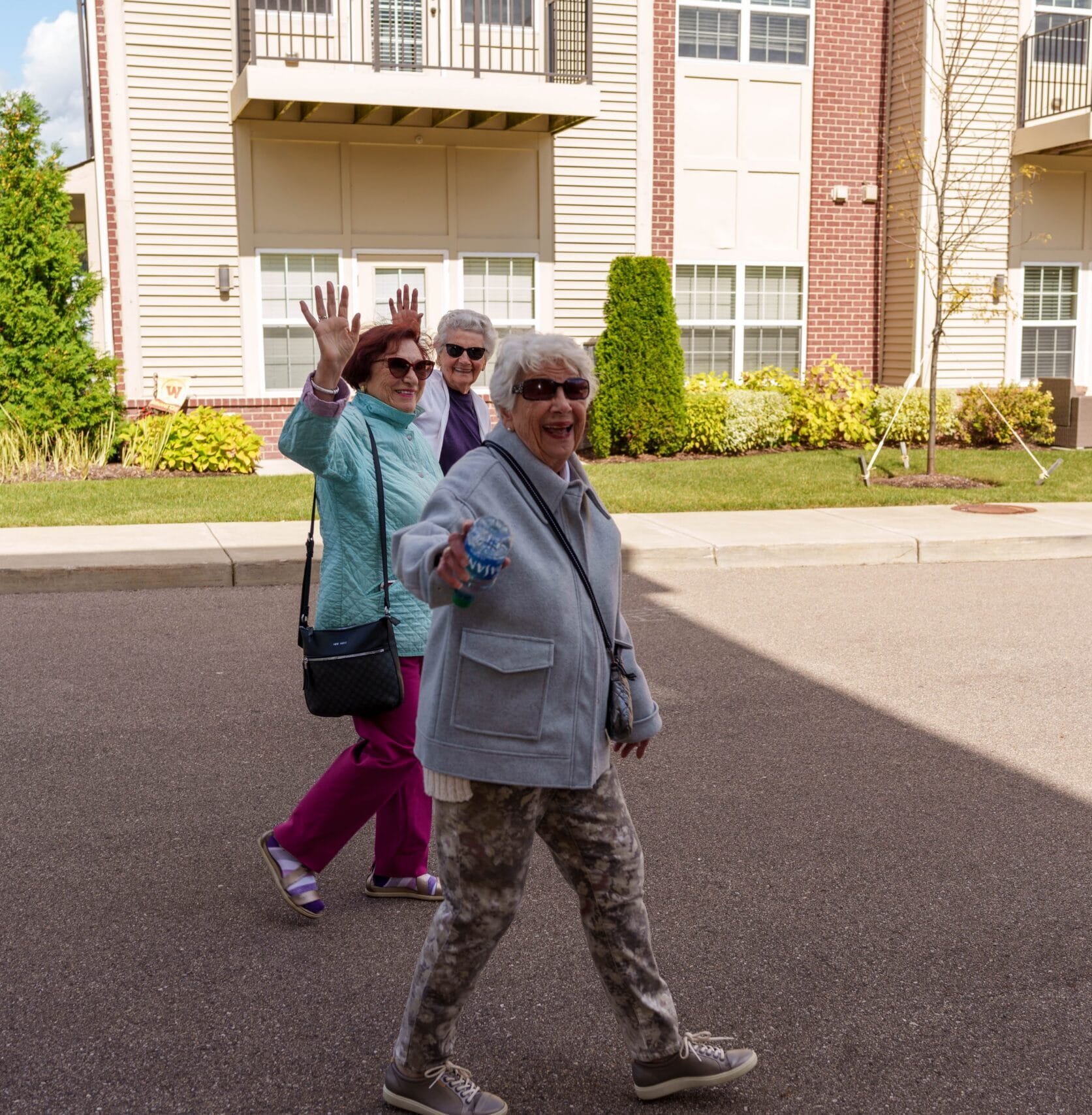 Senior women waving and smiling while taking a walk through All Seasons senior living community