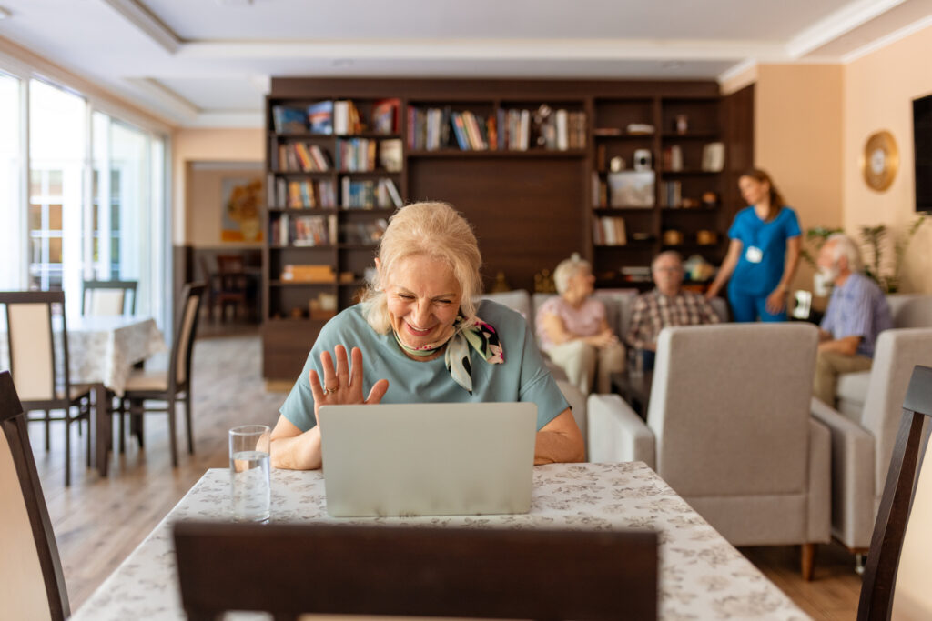 Smiling woman connecting with family on a call after the move to senior living.